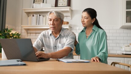 Grandmother comforting and supporting grandfather while looking at laptop show successful project and getting promotion. Happy senior businessman receive good news and talking to his wife. Myrmidon.