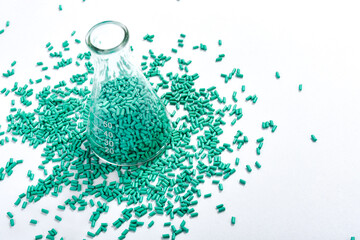 Turquoise masterbatch granules in Erlenmeyer flask isolated on white background, color pigment...