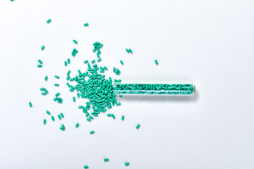 Turquoise masterbatch granules in glass tube isolated on white background, color pigment carrier polymer in plastic industry. Suitable for plastic industry catalog design