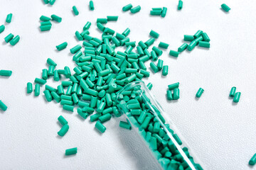 Turquoise masterbatch granules in glass tube isolated on white background, color pigment carrier...