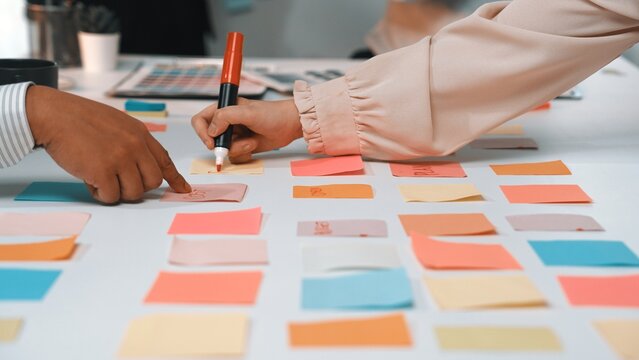 Two hands engage with colorful sticky notes on a table, showcasing a vibrant brainstorming session in a collaborative workspace to generate innovative ideas and strategies. SACTR