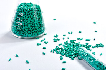 Turquoise masterbatch granules in Erlenmeyer flask and glass tube isolated on white background,...