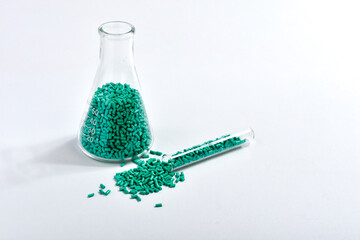 Turquoise masterbatch granules in Erlenmeyer flask and glass tube isolated on white background,...