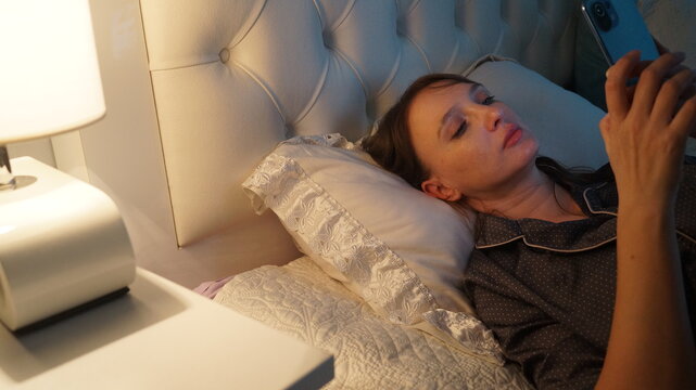 Woman with cellphone at night time in bed
