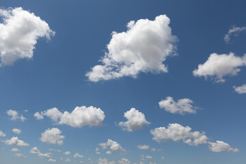 Clear blue sky with a few clouds and sun. The sky is very bright and the clouds are scattered throughout