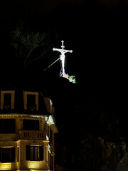 Old low-rise buildings of Karlovy Vary against the backdrop of a large illuminated cross at night