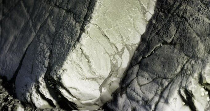 Detailed textures and lines are visible on a stone surface, highlighting the natural beauty of the rock. Soft lighting enhances the contours and crevices, creating an artistic display.