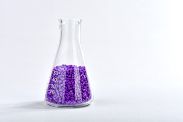 Purple masterbatch granules in Erlenmeyer flask isolated on white background, color pigment carrier...