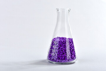 Purple masterbatch granules in Erlenmeyer flask isolated on white background, color pigment carrier...