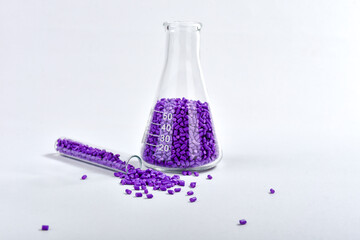 Purple masterbatch granules in Erlenmeyer flask and glass tube, isolated on white background, color...