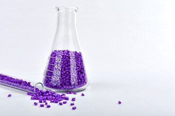 Purple masterbatch granules in Erlenmeyer flask and glass tube, isolated on white background, color...