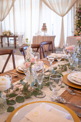 A wedding table centerpiece sits pretty in a gold compote bowl. The arrangement features white roses, ranunculus, and pastel carnations