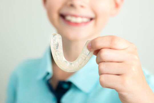 Close -up. A smiling child holds elainers in his hands, kapa for aligning tooths. Eliners for correcting bite