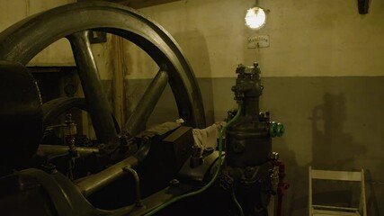 Overview of industrial machinery in an old power room, featuring wires and a large metal wheel. Industrial elements in the technical interior.