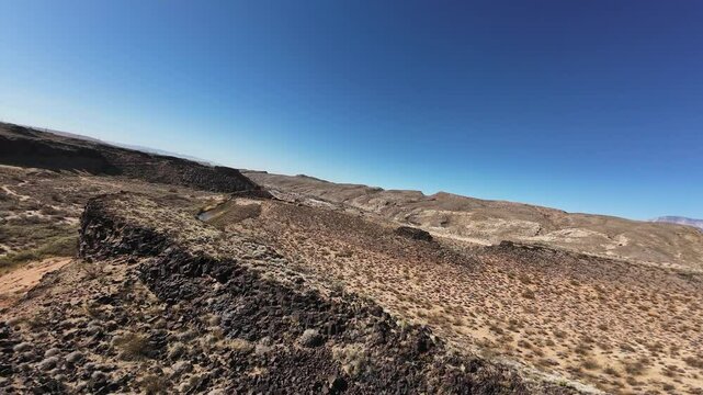 Virgin River Gorge- Hurricane, Utah, USA - February 10, 2025: Aerial-FPV-Flying over basalt rock outcropping on canyon rim-Dive to river with low flight skimming the top of the shallow river