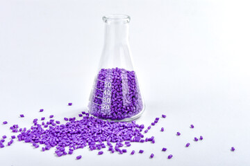 Purple masterbatch granules in Erlenmeyer flask isolated on white background, color pigment carrier...