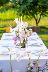 Wedding table set and decorated with pink flowers on a green lawn