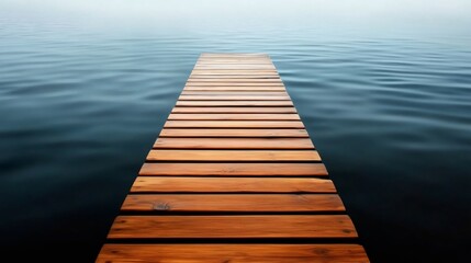 Obraz premium Wooden footbridge leading into a calm lake on a foggy day