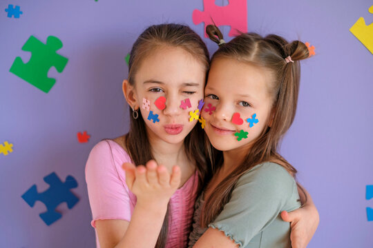 A girl blows a kiss while hugging her sister with autism spectrum disorder. Problems of education