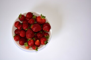 Fresh strawberries bowl on a white background top view. Full bowl of red juicy strawberries.