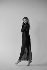 Young beautiful woman in black transparent dress posing in studio