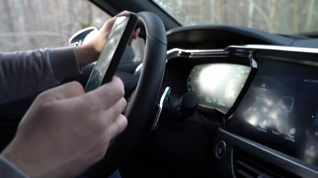 Moscow 09 May 2024. A man is driving a car and looking at his cell phone. The car is equipped with a steering wheel that has a built-in cell phone holder