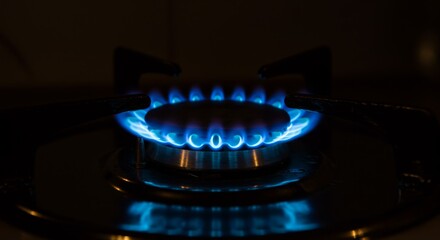 Blue Gas Flame on Stovetop - Close-up of a blue gas flame burning on a modern stovetop in the dark