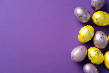 Vibrant Easter eggs with metallic accents on a purple background. Flat lay, top view, minimal style.