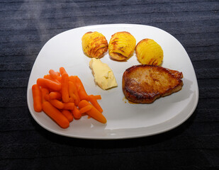 A pleasing meal features a grilled pork chop paired with golden roasted potatoes and vibrant...