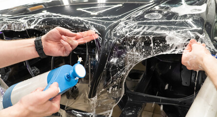 A car wrapping specialist applies a polyurethane film to the car. Selective focus. PPF protective...