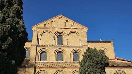 A historic brick church facade with arched windows and decorative details stands against a clear...