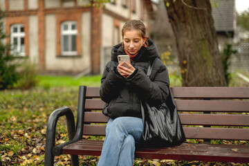 Girl Sitting On A Bench Talking On The Phone In Spring Park