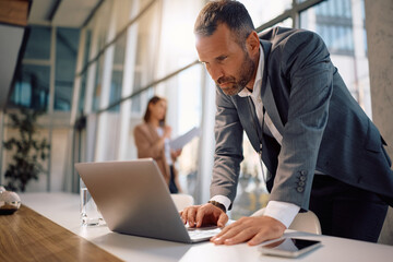 Male CEO working on computer in office.