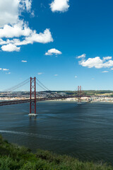 25th of April Bridge. Ponte 25 de Abril Suspension Bridge and Lisbon Skyline. Blue Sky and Cumulus Fluffy Clouds. Portugal