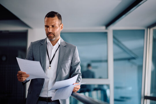 Mid adult businessman analyzing documents while working in office.
