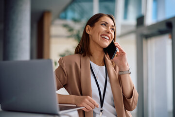Happy female entrepreneur talking on phone while working in office.