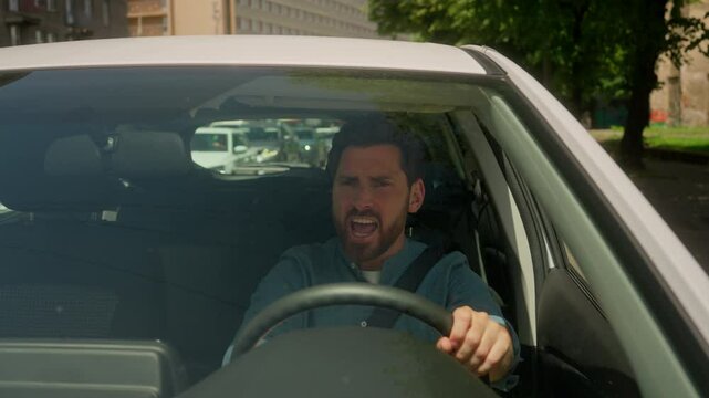 Angry irritated Caucasian man annoyed businessman male guy driver stuck traffic jam road accident problem driving honk car horn sound signal beep steering wheel shout anger displeased drive automobile