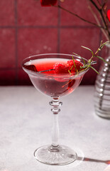 Red cocktail with raspberries and rosemary in elegant glassware for valentine's day celebration