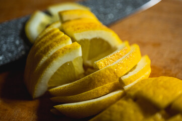 rich in vitamin C, freshly cut lemon on wooden background with sharp knife. Bright citrus fruit, ideal for cooking, drinks and healthy lifestyle, virus prevention, selective focus