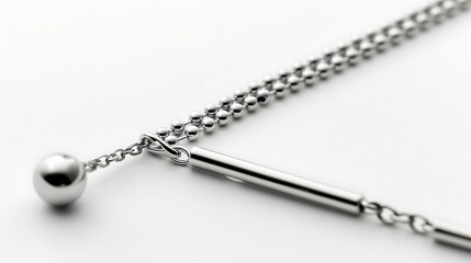 A minimalist silver necklace featuring a delicate ball and sleek bar pendant, elegantly designed with a fine beaded chain, showcasing simple sophistication against a bright backdrop.