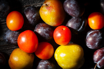 plums mix on black wood background top view