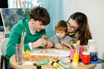 Fototapeta premium Young family with their son painting and having fun in the room