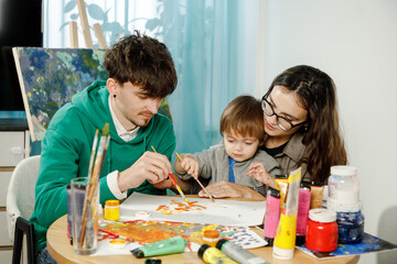 Obraz premium Young family with their son painting and having fun in the room
