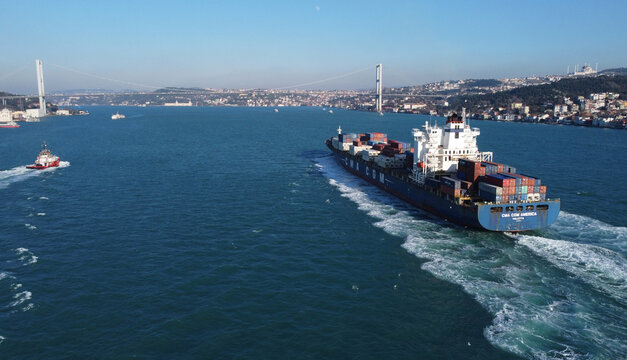 Istanbul, Turkey - January 14, 2022: CMA CGM container ship, third largest container shipping company in the world, sailing through Bosporus strait. Tugboat is seen on the left.