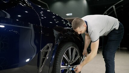 Obraz premium Mechanics tightening car wheel bolts in auto repair shop