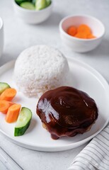 Asian meet hamburger with sauce, rice and vegetables in a plate