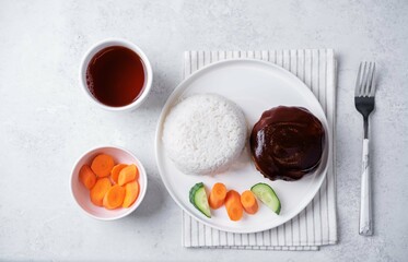 Asian meet hamburger with sauce, rice and vegetables in a plate