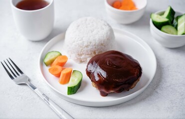 Asian meet hamburger with sauce, rice and vegetables in a plate
