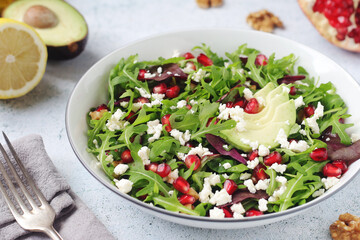 A plate with green rocket salad with pomegranate and avocado	
