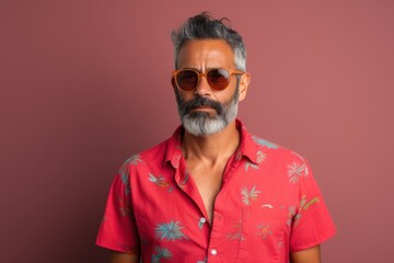 Fototapeta premium A man with a beard and glasses is wearing a red shirt with palm trees on it
